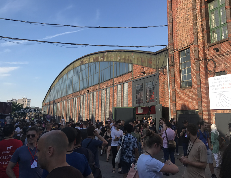 Conference attendees outside a large industrial hall.